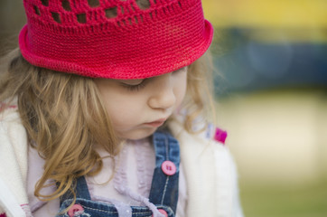 Shallow depth of field close up shot of a cute girl with curly blonde hair. She looks sad and lonely. Looking down.