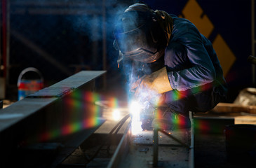 Asian Welder Industry with Torch and Protective Helmet in Large Welding Section