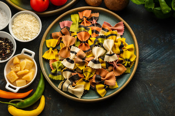 Not cooked farfalle pasta, with a set of products and ingredients for cooking traditional Italian food