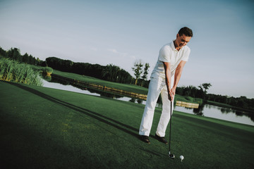 Young Man in White Clothes Playing Golf on Field.