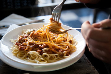 Mann isst Spagetti Bolognese Pasta mit Löffel und Gabel im Restaurant
