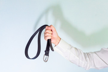Office Man in white shirt and tie is holding a belt, punishment concept