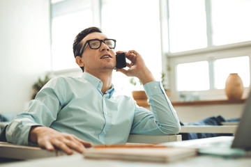 Phone conversation. Nice handsome man talking on the phone while working in the office