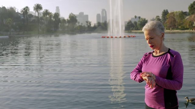 71 year old woman checks her step counter to see how her workout is going.