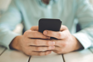 Modern gadget. Close up of a black smartphone being in hands of a nice young man