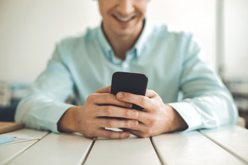 Digital device. Close up of a modern smartphone being held by a joyful young man