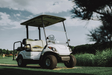 White Little Cart on Golf Field in Sunny Day.