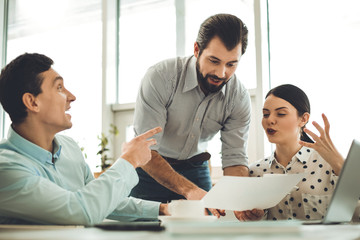 Business plan. Nice skilled man holding a document while discussing business with his colleagues
