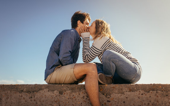 Romantic couple sitting on a sea wall