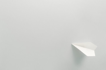 White paper plane on light blue background. Flat lay, top view. Concept of freedom and travelling
