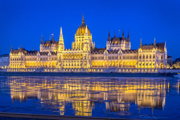 Fototapeta na wymiar Night view of illuminated Hungarian Parliament Building is seat of National Assembly of Hungary with beautiful reflection during spring on ice drift Danube River, Budapest, Hungary.