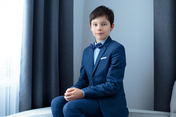 Cute school boy in dark classic suit indoors