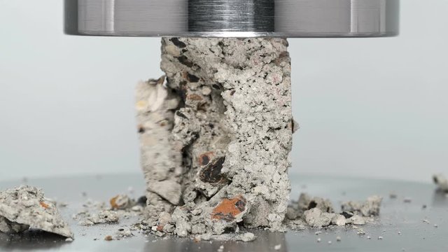 building block of cement and stone tested and tested for strength by hydraulic press, close-up