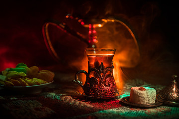 Hookah hot coals on shisha bowl making clouds of steam at Arabian interior. Oriental ornament on the carpet eastern tea ceremony. Stylish oriental shisha in dark with backlight.