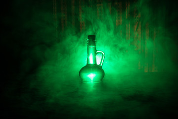 Antique and vintage glass bottles on dark foggy background with light. Poison or magic liquid...