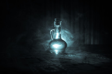 Antique and vintage glass bottles on dark foggy background with light. Poison or magic liquid...