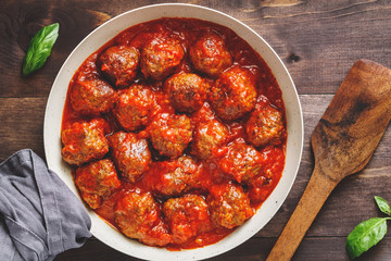 Tasty beef frying meatballs in tomato sauce in a white pan on a kitchen table. Food photography, top view, Sweden traditional cuisine.