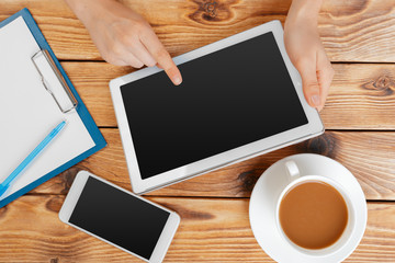 Girl hands with digital tablet and cup of coffee on a wooden table