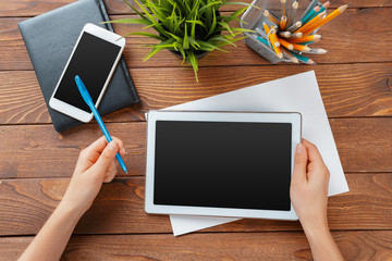 woman holding blank tablet device over a wooden workspace table