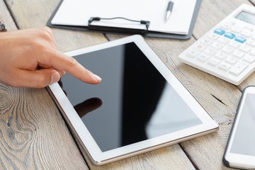 hands of a man holding tablet device over a wooden workspace table