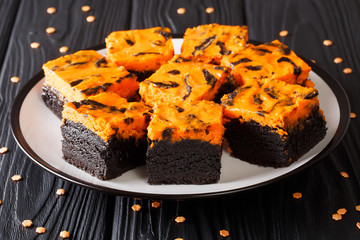 Halloween sweetness Cream Cheese Brownies cake black with orange color close-up on a plate. horizontal