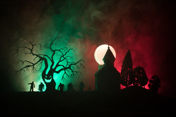 Scary view of zombies at cemetery dead tree, moon, church and spooky cloudy sky with fog, Horror...