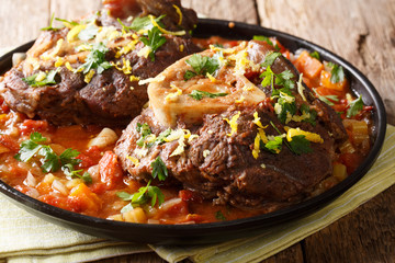 Delicious Italian veal steak Ossobuco alla Milanese with gremolata and vegetable sauce close-up....