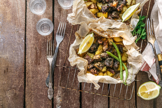Traditional Greek kleftiko, an oven-baked lamb stew with potato, olive oil, onion, carrot, garlic and herbs, served with lemon and ouzo. copy space