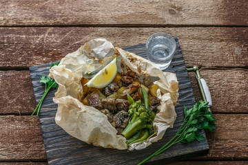 Lamb kleftiko, potato and vegetables served on wooden cutin board, rustic style