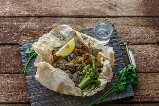 Lamb kleftiko, potato and vegetables served on wooden cutin board, rustic style