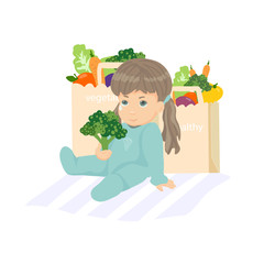 Cute baby girl sitting on the floor. Doesn't want to eat broccoli. Shopping bags with vegetables 