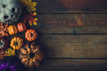 Creative autumn Halloween layout with various leaves and pumkins on dark wooden backgound. Flat lay.