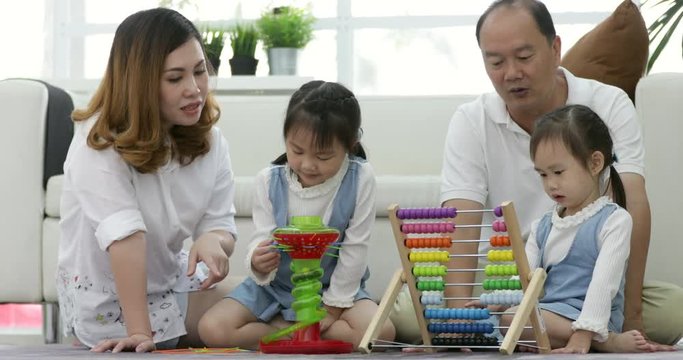 Happy asian family with two daughters playing at home. Family sitting on floor and playing together.