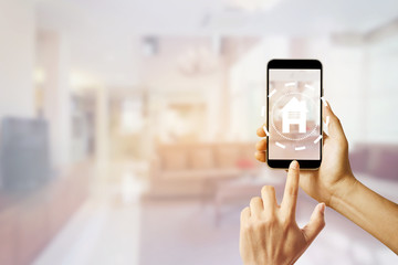 Hold a mobile phone with a smart home app on the background in the home.