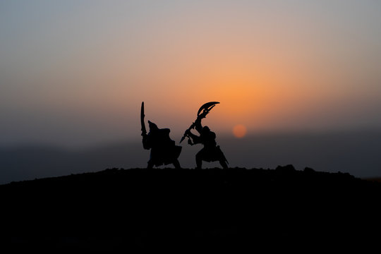 Medieval battle scene on sunset. Silhouettes of fighting warriors on sunset background.