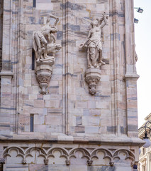 Fototapeta premium Vertical: Closeup detail of the intricate artistry, sculpture, window work,spires, marbel bricks of exterior of the Duomo di Milano