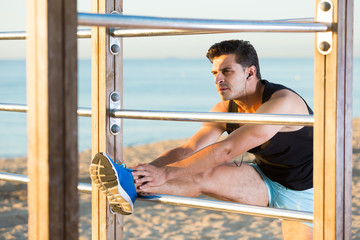Man stretching on wall bars on beach