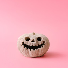Carved Halloween pumpkin on pastel pink background. Creative Halloween minimal concept.