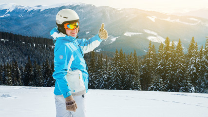 Woman skier in a white and blue suit at the mountain top in snow