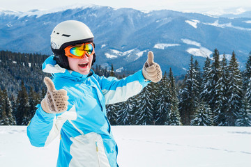 Woman skier in a white and blue suit at the mountain top in snow