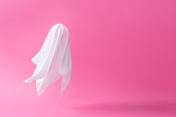 White ghost sheet costume against pastel pink background. Minimal Halloween scary concept. - obrazy, fototapety, plakaty