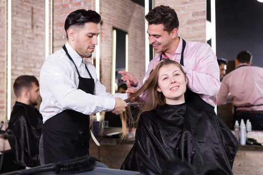 Two hairdressers making hairstyle for female client