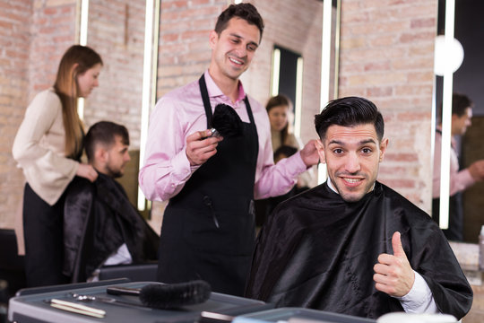 Satisfied man approving result of hairdresser work