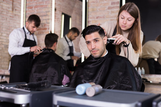 Hairdresser doing styling of guy with electric hair clipper