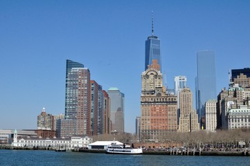 Fototapeta na wymiar Île de Manhattan et one world trade vue d'Ellis Island par une journée ensoleillée et un ciel bleu sans nuage à New York, États-Unis