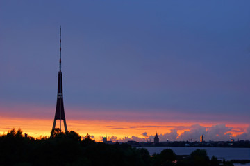 Fototapeta na wymiar Summer sundown after storm in Riga, television tower on the front and trees and city buildings on the background on the horizon