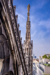 Vertical: Rooftop view of spires, sculpture, cathederal, and Milan from the Duomo di Milano