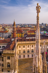 Vertical: Rooftop view of spires, sculpture, cathederal, and Milan from the Duomo di Milan