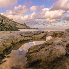 Obraz premium Sunset reflected on puddle of sea water in Porto Torres