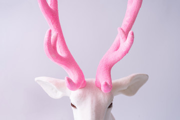 White reindeer with glitter pink antlers. Minimal New Year or Christmas background concept.